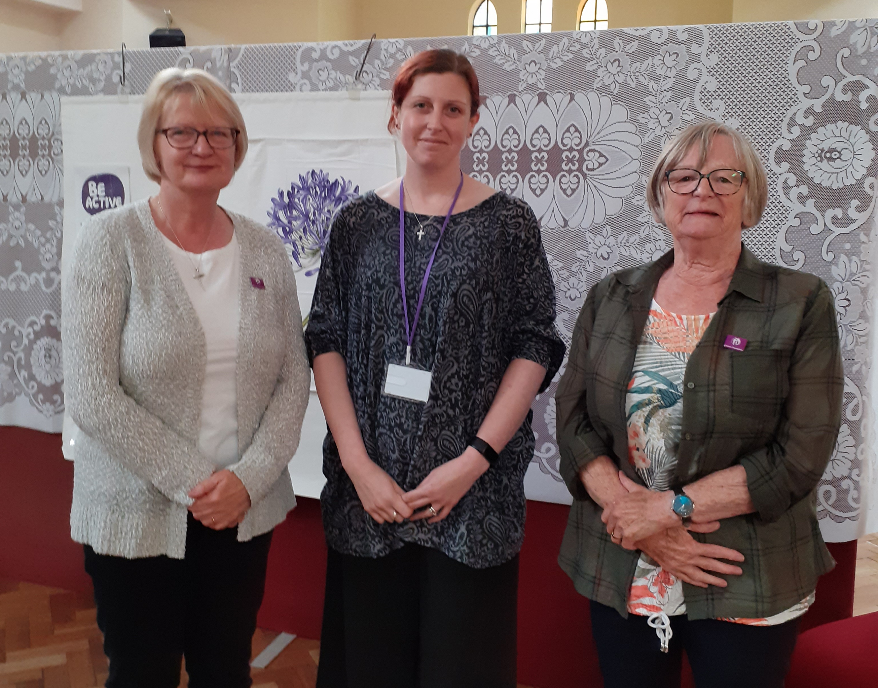 Three women standing in a row, two of which are wearing Carer’s Champion badges